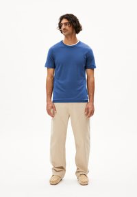 Blauw T-shirt met korte mouwen en een ronde halslijn, gecombineerd met beige cargobroek. De broek heeft zichtbare stiksels en zakken.