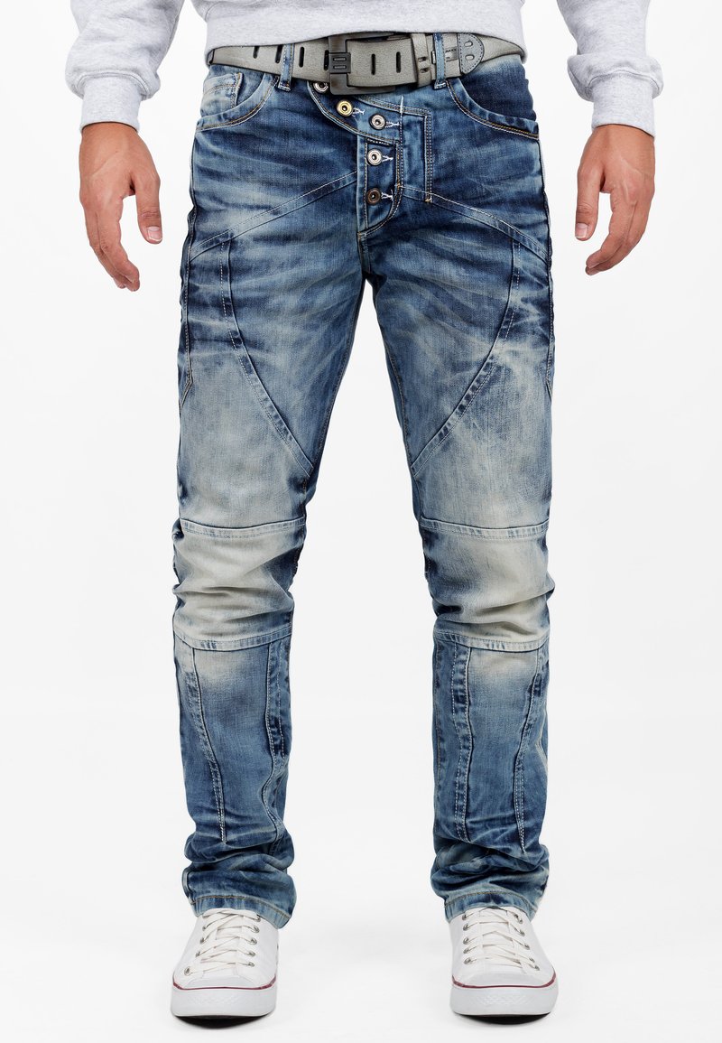 Jeans en denim bleu avec une finition décolorée et texturée. Dotés d'une braguette zippée, de plusieurs boutons et d'une coupe slim avec des détails sur les panneaux de genoux.