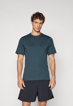 Tmavomodrá tričká s krátkym rukávom vyrobená z mäkkej tkaniny, s okrúhlym výstrihom a malým čiernym logom Nike na ľavej hrudi.