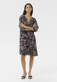 Robe imprimée à coupe ample, présentant une base beige avec des motifs floraux bleu foncé, un décolleté en V profond et des manches bouffantes trois-quarts.