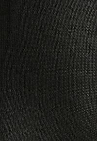 Zwart ribstof met een gestructureerd patroon van verticale lijnen, met een zachte en rekbare uitstraling die geschikt is voor aansluitende kleding.