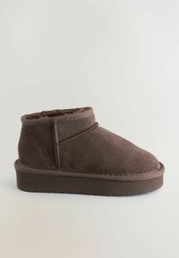 Braune Wildleder-Ankelstiefel mit weicher Innenausstattung, niedriger Höhe und abgerundeter Zehenpartie. Verfügt über Kontrastnähte und eine flache Gummisohle.