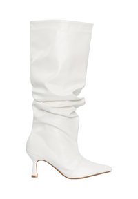 Bota blanca holgada hasta la rodilla con punta afilada y tacón delgado de altura media, con textura de cuero suave y suela marrón claro.