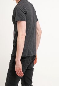 Camiseta gris oscura de manga corta, cuello redondo y corte slim. La tela parece suave con una textura lisa. Sin patrones ni acentos visibles.