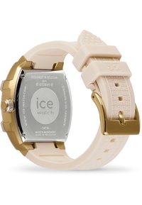 Reloj con fondo de oro y correa de silicona color crema. Presenta un diseño de correa texturizada y fondo de acero inoxidable. Resistente al agua hasta 5ATM.