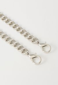 Chaîne en métal argenté avec des maillons entrelacés et deux crochets à ressort à chaque extrémité. Fini lisse avec une surface réfléchissante.