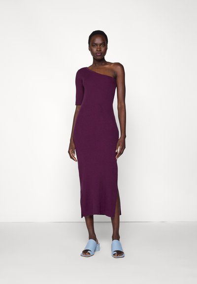 Vestido midi com nervuras de um ombro só em roxo profundo, com uma fenda lateral. Combinado com sandálias de salto bloco em azul claro. Textura suave em todo o tecido.