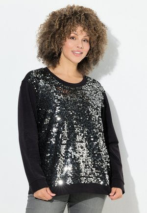 Sudadera negra de manga larga con un panel frontal de lentejuelas plateadas, con un corte holgado y puños acanalados. Textura suave en general.