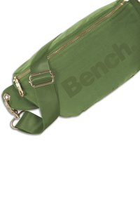 Groene stoffen heuptas met een gouden rits, verstelbare band en een opvallend "Bench." logo op de voorkant gedrukt.