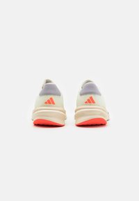 Adidas running shoes in light yellow mesh with grey accents, featuring a cushioned sole and bright orange rubber outsole.