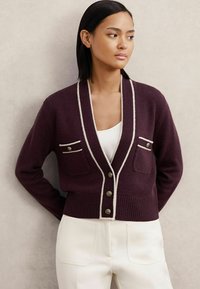 Cardigan burgund cu margini albe, dotat cu două buzunare pentru piept, guler în V și închidere cu nasture. Textură tricotată cu tiv și manșete cu nervuri.