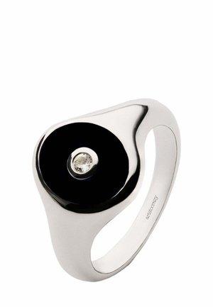 Anillo de plata con un centro circular negro brillante y una piedra preciosa clara en el centro. Diseño suave y curvado con un acabado pulido.