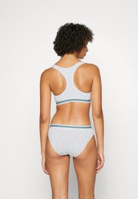 Szürke pamut sportmelltartó racerback kialakítással és csíkos elasztikus pánttal. Hozzá illő szürke pamut bugyi hasonló csíkos derékkal.