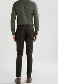 Groen gestreept overhemd met lange mouwen, gecombineerd met donkergroene slim-fit broek en bruine instappers.