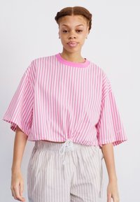 Top corto a righe rosa e bianche con maniche corte e orlo regolabile, abbinato a pantaloni a righe chiare.
