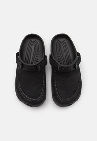 Black clogs with a textured rubber sole, adjustable strap, and molded footbed. Features white stitching and a smooth, durable surface.