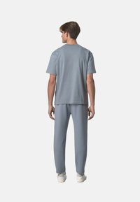 T-shirt in cotone grigio a maniche corte e pantaloni della tuta abbinati. Tessuto morbido, vestibilità comoda, senza disegni, abbinati a sneakers bianche.
