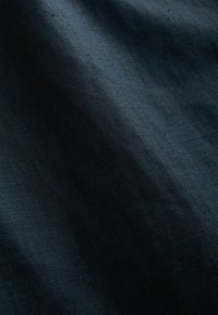 Mörkblått texturerat tyg, något skrynkligt med en slät yta. Medium vikt, med en subtil lyster och intrikat vävstruktur.