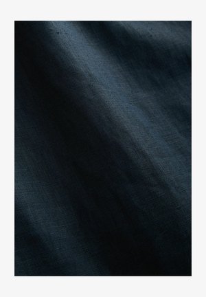 Tmavomodrá textúrovaná látka, mierne pokrčená s hladkým povrchom. Stredná hmotnosť, ktorá predvádza jemný lesk a zložitý tkaninový vzor.