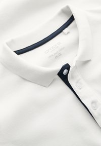 Polo blanc avec col intérieur bleu marine et patte de boutons, étiqueté 100 % coton pur, taille M/48.