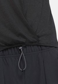 Gros plan d'un vêtement noir avec une ceinture élastique et un cordon de serrage réglable avec un motif noir et blanc.