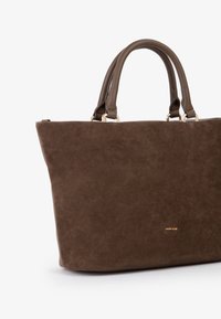 Borsa a tracolla in suede marrone con manici in pelle e piccolo logo dorato "MIRIADE" su sfondo bianco.