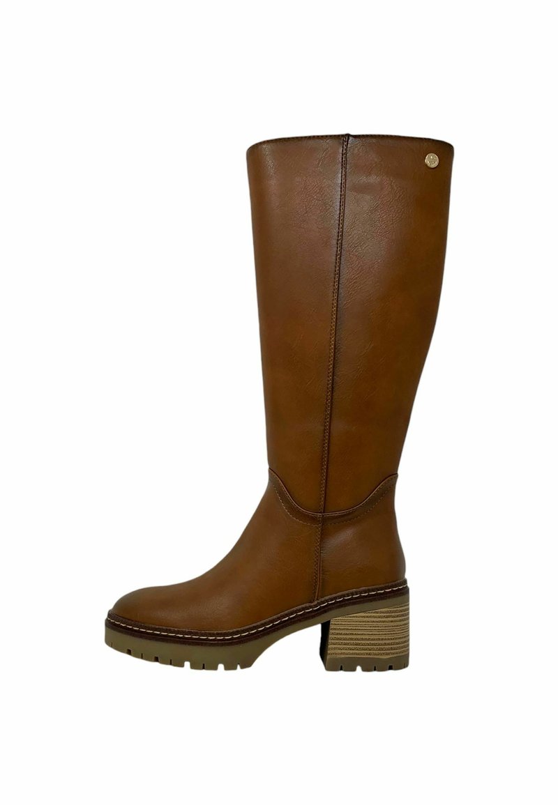 Bota de cuero marrón hasta la rodilla con un tacón grueso, punta redonda y detalles de costura. La suela es texturizada con un patrón de relieve pronunciado.