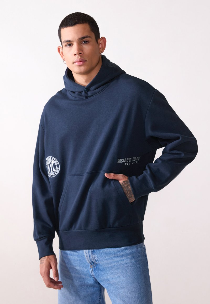 Marineblå hætte sweatshirt lavet af blødt stof, har en forlommek, broderede logoer og ribbede manchetter. Casual pasform med subtile tekstdetaljer.