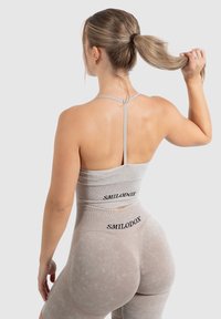 Conjunto de ropa deportiva gris con tirantes finos, que incluye un top corto ajustado y shorts de cintura alta. Textura suave con el detalle del logo "SMILODOX".