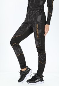 Sorte leggings med et geometrisk design, der har gyldne detaljer og en tætsiddende pasform. Fremstillet af strækbart, åndbart materiale.