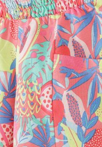 Tissu coloré avec des motifs de fruits tropicaux et de feuilles, comprenant des ananas, des grenades et divers détails de feuillage bleus et verts.