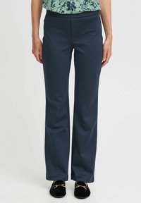 Dark navy blue pants made of stretch fabric, featuring a straight leg design and no visible fastenings, paired with black loafers.