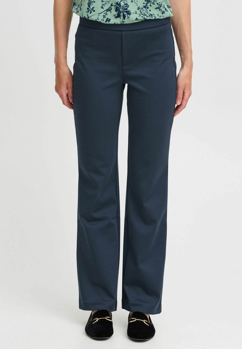 Dark navy blue pants made of stretch fabric, featuring a straight leg design and no visible fastenings, paired with black loafers.
