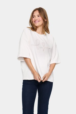 Oversized white sweatshirt with a textured design reading "love," featuring short sleeves and a crew neckline, paired with dark jeans.