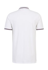 Vit polo-tröja med korta ärmar, ribbad krage med marinblå och röda ränder, slät bomullstextur, rak fåll och inga synliga logotyper.