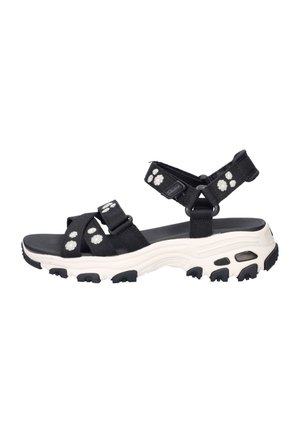 Sandale sportive noire avec semelle épaisse blanche, brides réglables et petits motifs de fleurs blanches sur les brides.