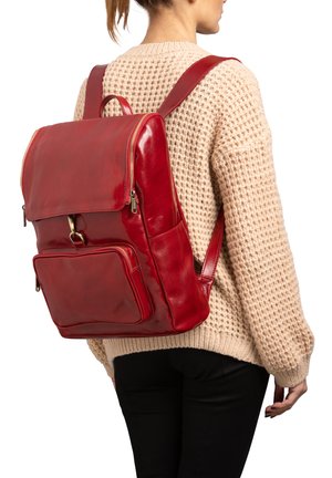 Zaino in pelle rossa con finitura lucida, dotato di un doppio ribalta, tasca frontale con zip e spallacci regolabili. Indossato sulla schiena.
