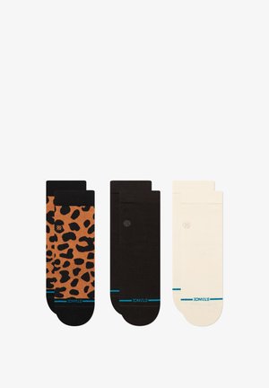 Three pairs of socks: one features orange with black leopard spots, one solid black, and one cream with blue accents at the cuffs.