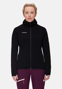Black fleece jacket with high collar, zip closure, and logo on the chest. Features two zippered side pockets and a smooth texture.
