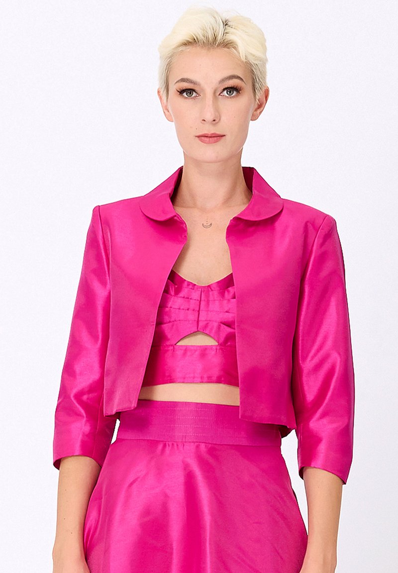Veste courte fuchsia avec un col arrondi et des manches trois-quarts, fabriquée dans un matériau satiné brillant, avec une coupe ajustée.