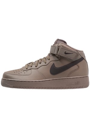 Mid-top Nike sneaker in lichtbruin leer met een gestructureerde afwerking, zwarte swoosh, verstevigde veterogen en een gewatteerde kraag.