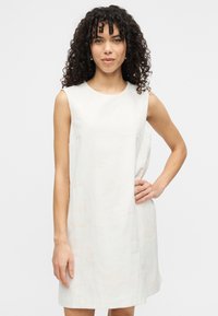 Αμάνικο φόρεμα σε γραμμή Α από ελαφρύ κρεμ ύφασμα, με διακριτικό ανάγλυφο σχέδιο. Το σχέδιο περιλαμβάνει στρογγυλή λαιμόκοψη και πλαϊνές τσέπες.