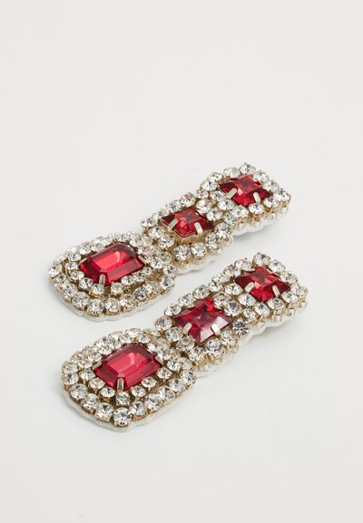 Par çift zlatnih naušnica s crvenim pravokutnim draguljima okruženim prozirnim rhinestones na bijeloj pozadini.