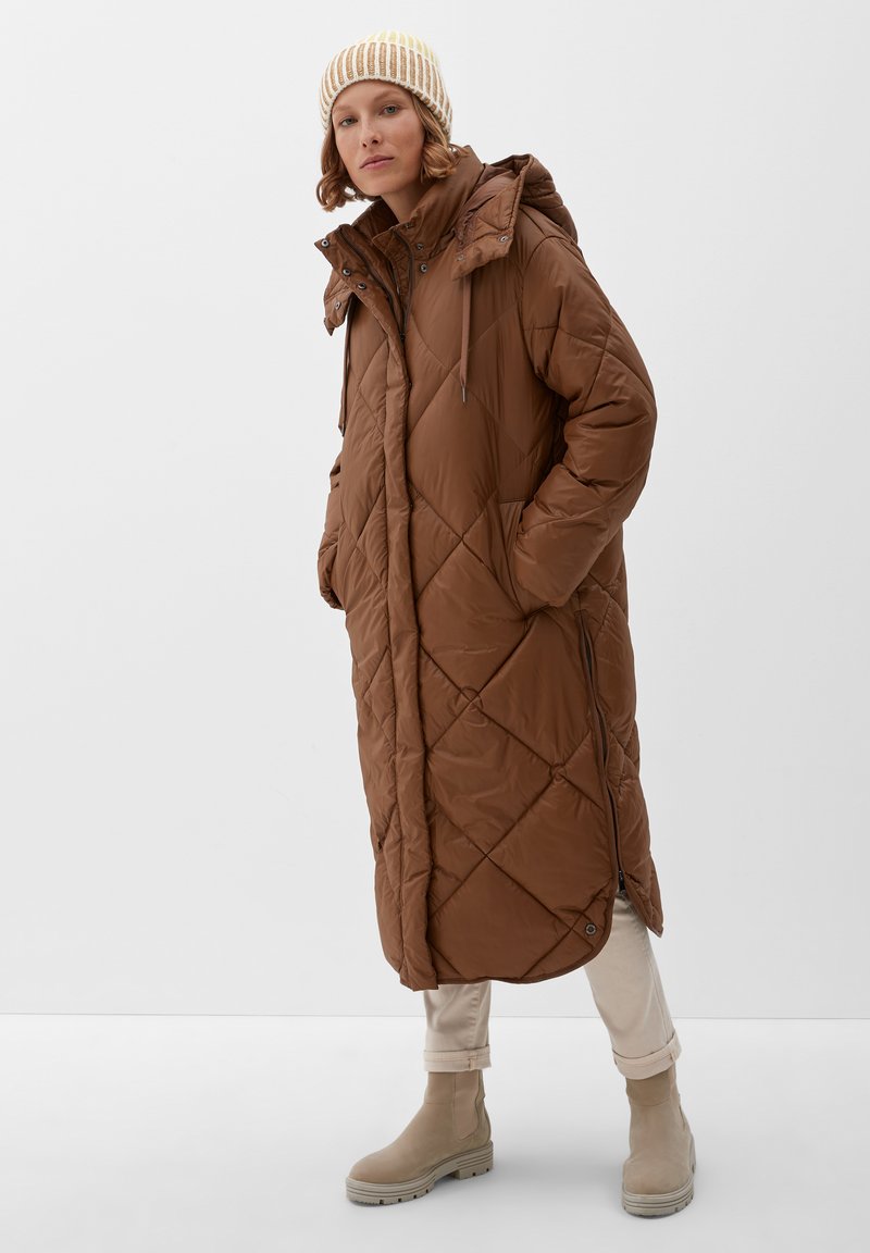 Bruine, gebandeerde lange jas met een capuchon en zijzakken. Gemaakt over crème kleuren broek en beige laarzen; heeft een gestructureerde, waterafstotende stof.