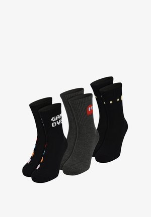 Drei Paare von Socken bis zur Mitte der Waden mit Designs im Retro-Videospielstil: schwarz mit "GAME OVER", grau mit rotem Geist und schwarz mit gelben Punkten.