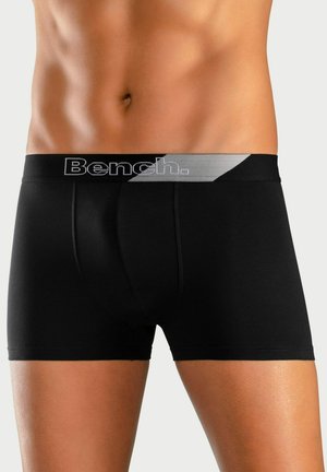 Black boxer briefs with a grey elastic waistband featuring "Bench." logo, smooth fabric, and a fitted design contouring the body shape.