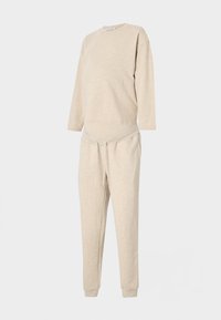 Ensemble sweat-shirt et pantalon beige en matériau doux, avec un col rond, des manches longues et une taille à cordon. Coupe régulière.