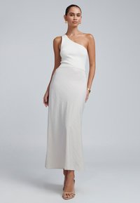 Haut blanc côtelé à une épaule associé à une jupe maxi fluide gris clair avec une texture lisse et un motif diagonal subtil.