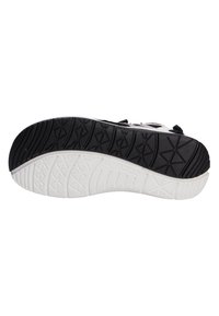 Svart och vit gummi sneaker sula med texturerade mönster. Har en böjd kant och uttalad mönstring för grepp. Varumärket synligt.
