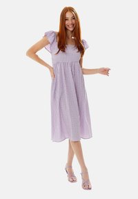 Lilac and white gingham dress with short ruffled sleeves, square neckline, and a flowing A-line design, paired with lavender strappy sandals.